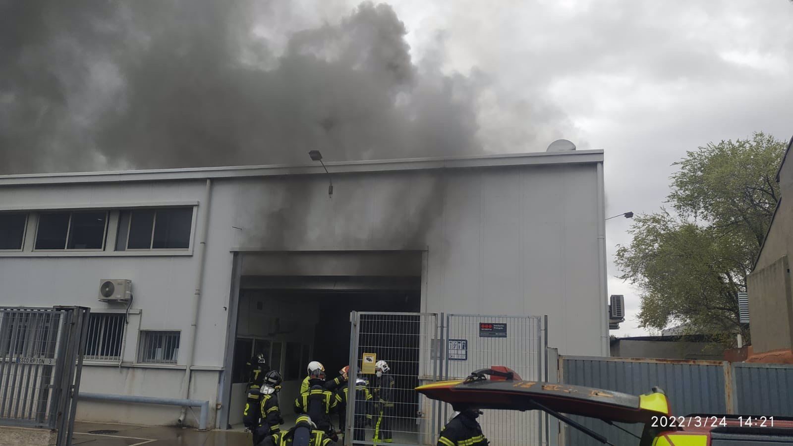 Los bomberos extinguen un incendio en una nave de reparación y pintura de vehículos en Barajas